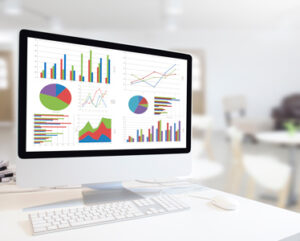 Nowoczesny komputer z klawiaturą i myszą na stole, pokazujący wykresy