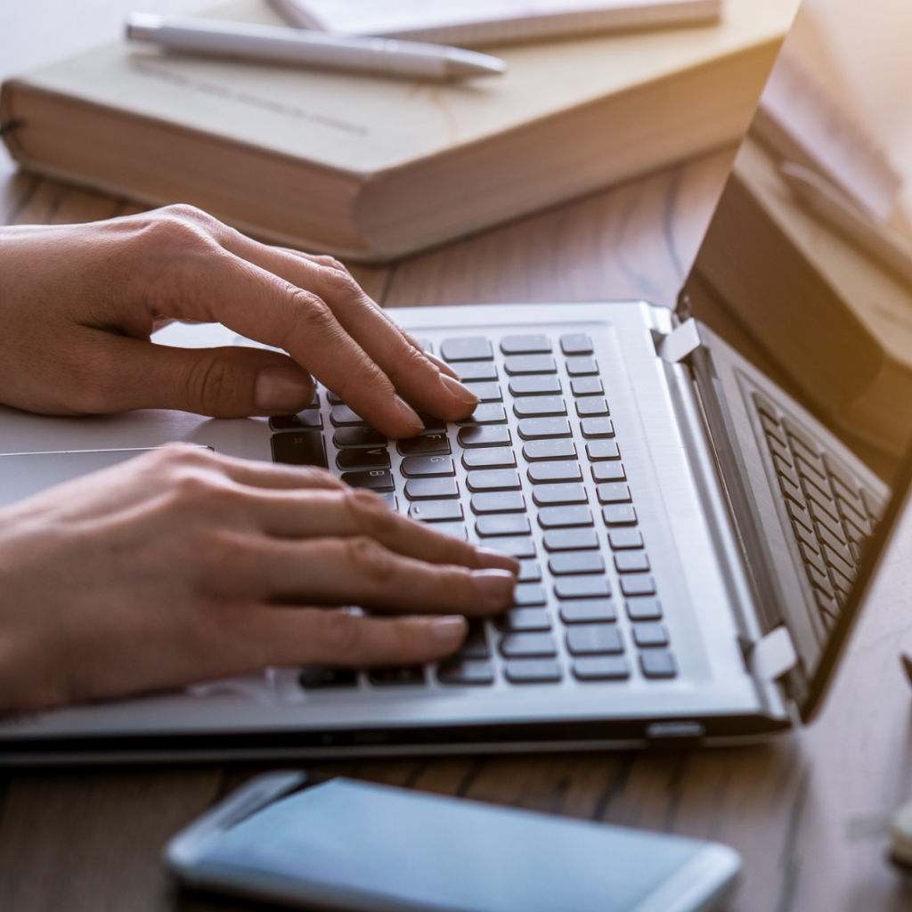 Ręce piszące na klawiaturze laptopa